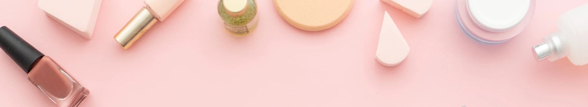 kosmetyki leżące na różowym biurku